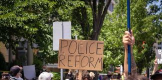 Protesters holding a cardboard sign reading Police Reform