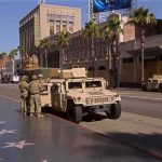Tourist Paradise Turns War Zone Soldiers beside a military Humvee on a palm-lined city street