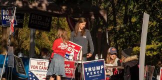 People at a campaign booth with political signs outdoors