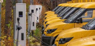 Row of yellow electric vans charging at stations