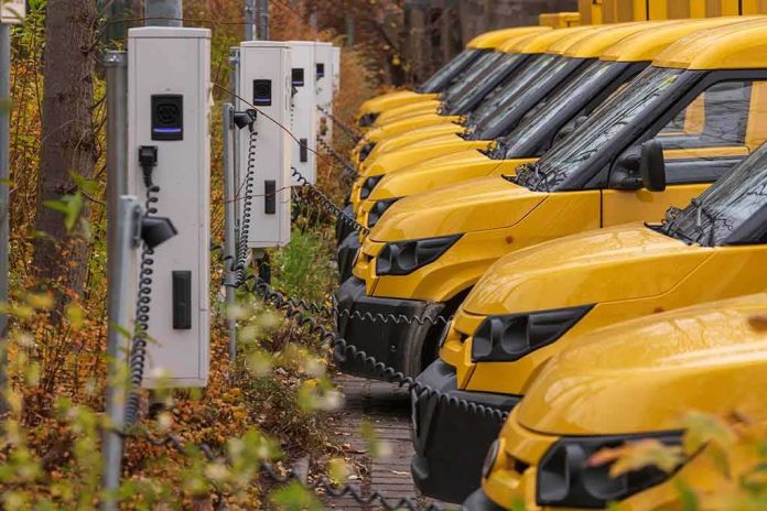 Row of yellow electric vans charging at stations