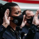 Police officers wearing masks raise right hands during oath ceremony