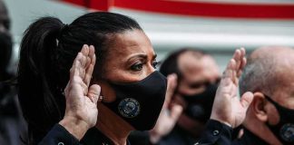 Police officers wearing masks raise right hands during oath ceremony