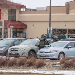 police officers in tactical gear beside cars in a snowy parking lot