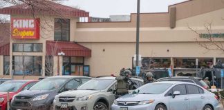 police officers in tactical gear beside cars in a snowy parking lot