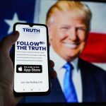 Smartphone showing Truth Social app screen with Donald Trump on a U.S. flag backdrop