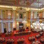 Legislative chamber with red carpet and chandeliers