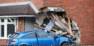 Blue car crashed into brick house wall