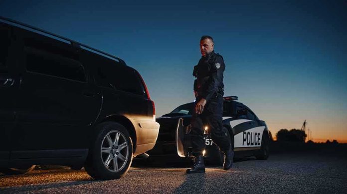 shutterstock_2232055247 Police officer standing near patrol car during twilight traffic stop