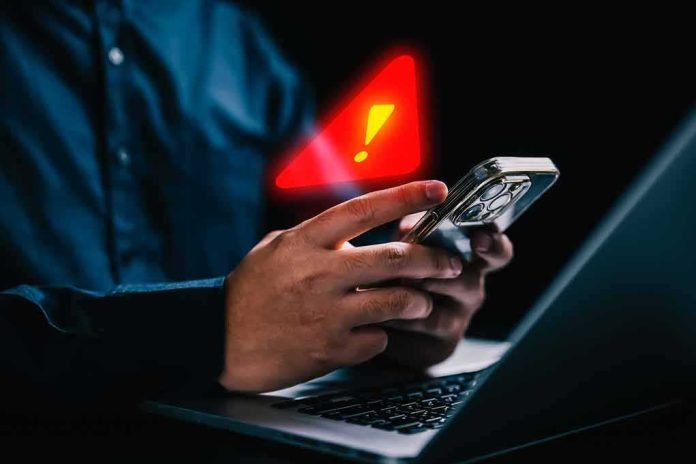 hands holding smartphone with warning alert icon