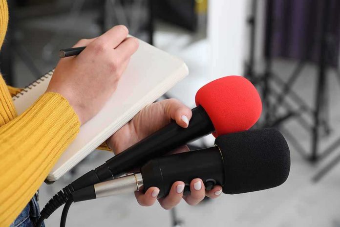 shutterstock_2431198207-5 Journalist holding two microphones while writing in a notebook