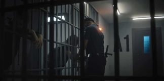 police officer at a jail cell with detainees behind bars