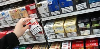 Hand selecting a pack of cigarettes from a store shelf