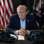 Donald Trump seated at a table between two desk phones