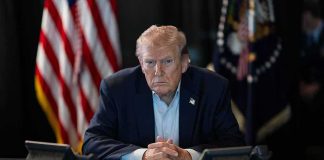 Donald Trump seated at a table between two desk phones