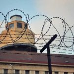 Barbed wire fence in front of a prison watchtower