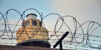 Barbed wire fence in front of a prison watchtower