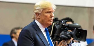 Donald Trump speaking with media cameras in the background