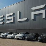 Tesla cars parked outside a large Tesla building