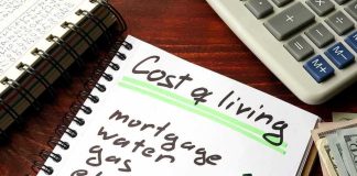 Budget notebook with cost of living list, calculator, and cash
