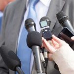 Microphones held toward a person in a suit