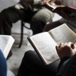 Hands holding open books in a small discussion circle