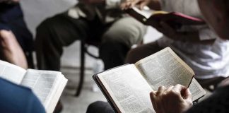 Hands holding open books in a small discussion circle