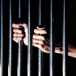 hands gripping prison bars
