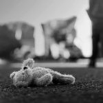 Stuffed toy lying on pavement in black and white
