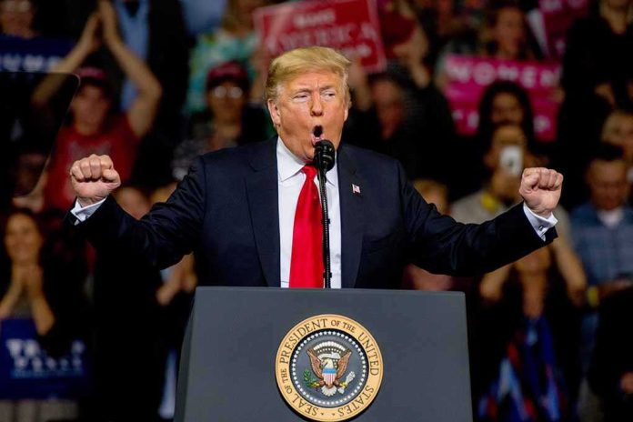 shutterstock_1204270501 Donald Trump speaking at a rally podium with arms raised