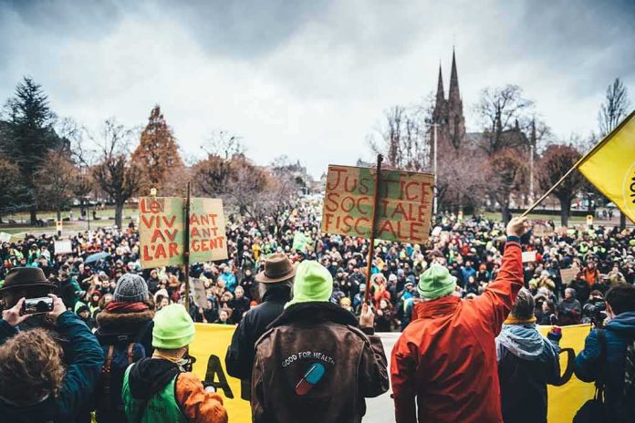 Christian Jones at a large outdoor protest with crowds and handmade signs