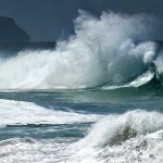 Crashing ocean waves against the shore under a cloudy sky