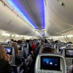 Airplane cabin with passengers seated and seatback screens