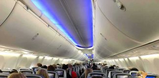 Airplane cabin with passengers seated and seatback screens