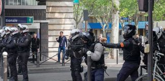 Riot police in helmets line a city street during an operation
