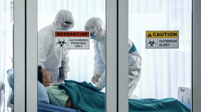 shutterstock_1647350797-1 Healthcare workers in hazmat suits treat a patient in a quarantine room