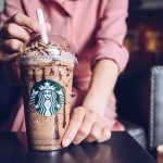 Iced blended coffee drink with chocolate drizzle held by a person