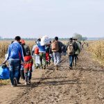 Group of people walking along a muddy rural path between fields