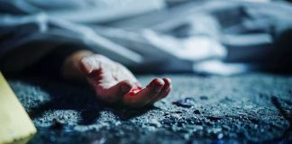 Human hand on gritty ground near a covered body