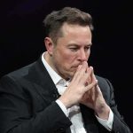 Elon Musk seated with hands steepled in thought
