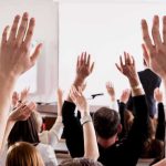 Audience raising hands in a lecture hall