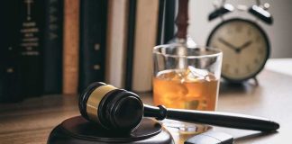 Judge's gavel with car key and whiskey glass on desk