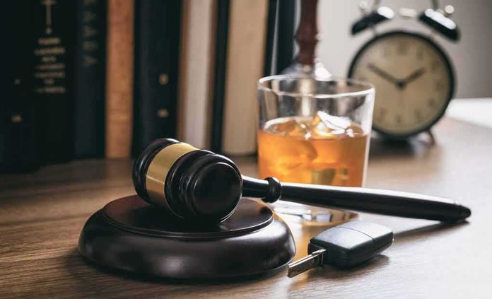 Judge's gavel with car key and whiskey glass on desk