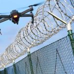 Drone flying near barbed wire security fence